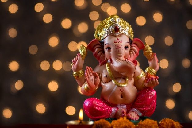 an elephant statue sitting on top of a table next to some flowers and candles with lights in the background