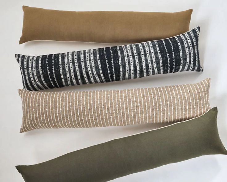 four pillows lined up on top of each other in different colors and patterns, one is black, the other brown