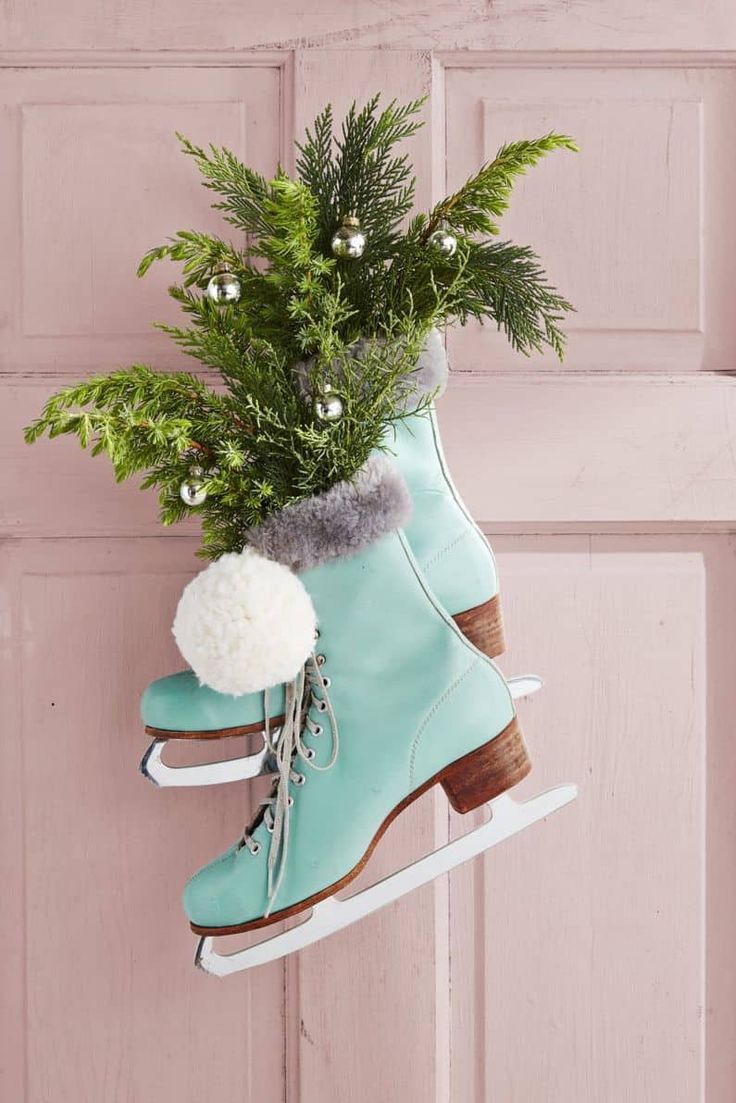 a pair of ice skates hanging from a door handle with plants in it and snowballs on top