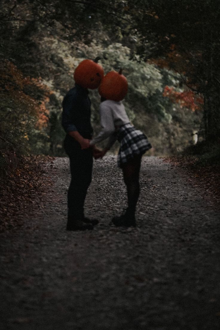 two people with red balloons on their heads standing in the middle of a forest path