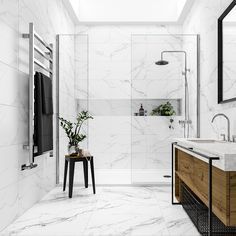 a bathroom with white marble walls and flooring, along with a wooden vanity sink