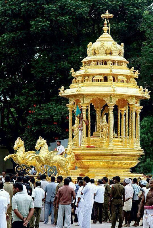 people are standing around in front of a large golden structure with horses and chariots on it