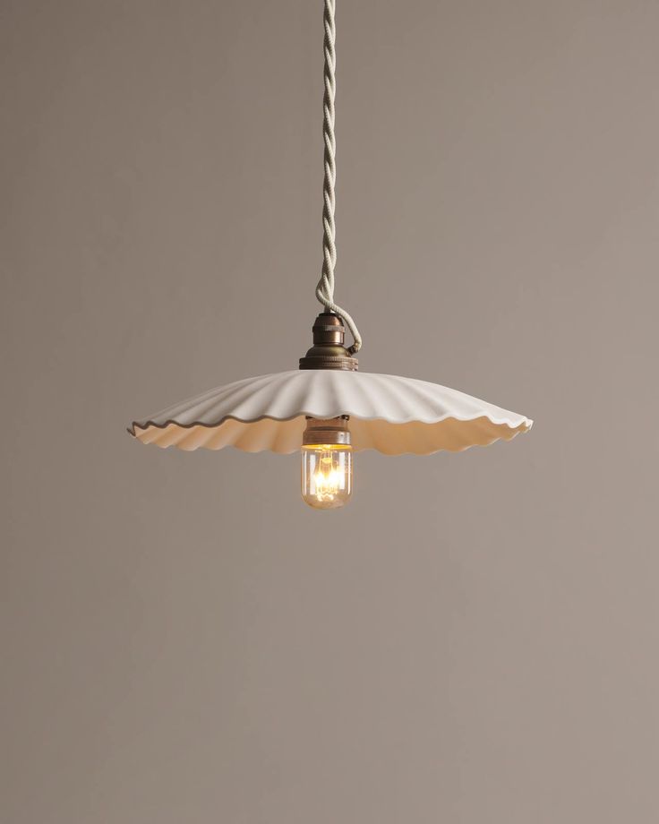 a light hanging from a ceiling fixture with an umbrella shade on the top and bottom