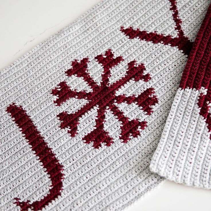 two red and white crocheted items sitting on top of a table next to each other