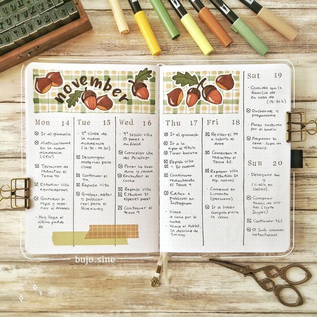 an open planner with markers and pencils next to it on top of a wooden table