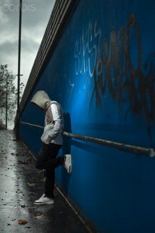 a person leaning against a blue wall with graffiti on it and an umbrella over their head