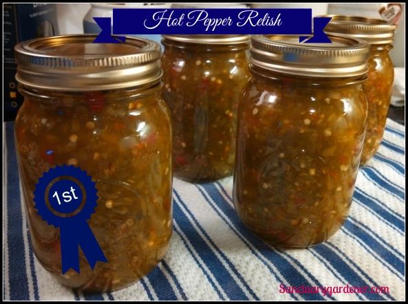 four jars filled with pickles sitting on top of a blue and white table cloth