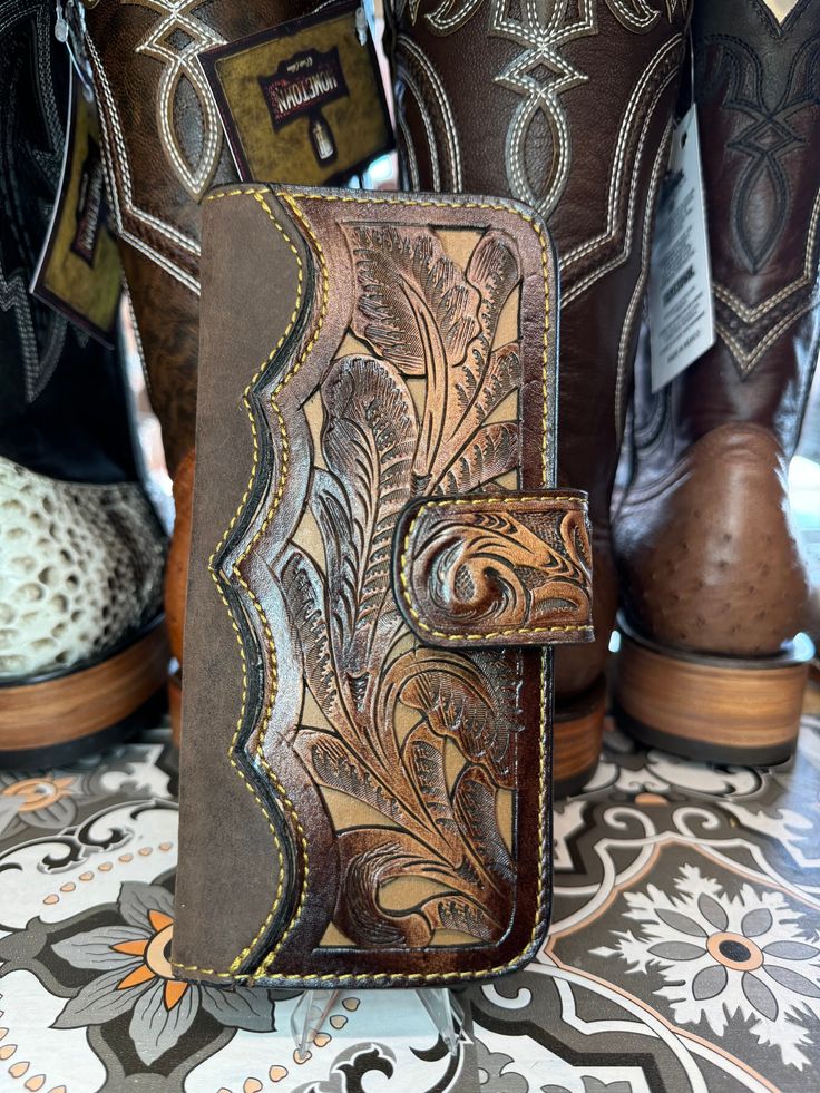 a brown leather wallet sitting on top of a table next to cowboy boots and other items