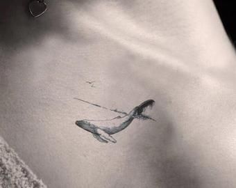 a black and white photo of a woman's stomach with a whale tattoo on it