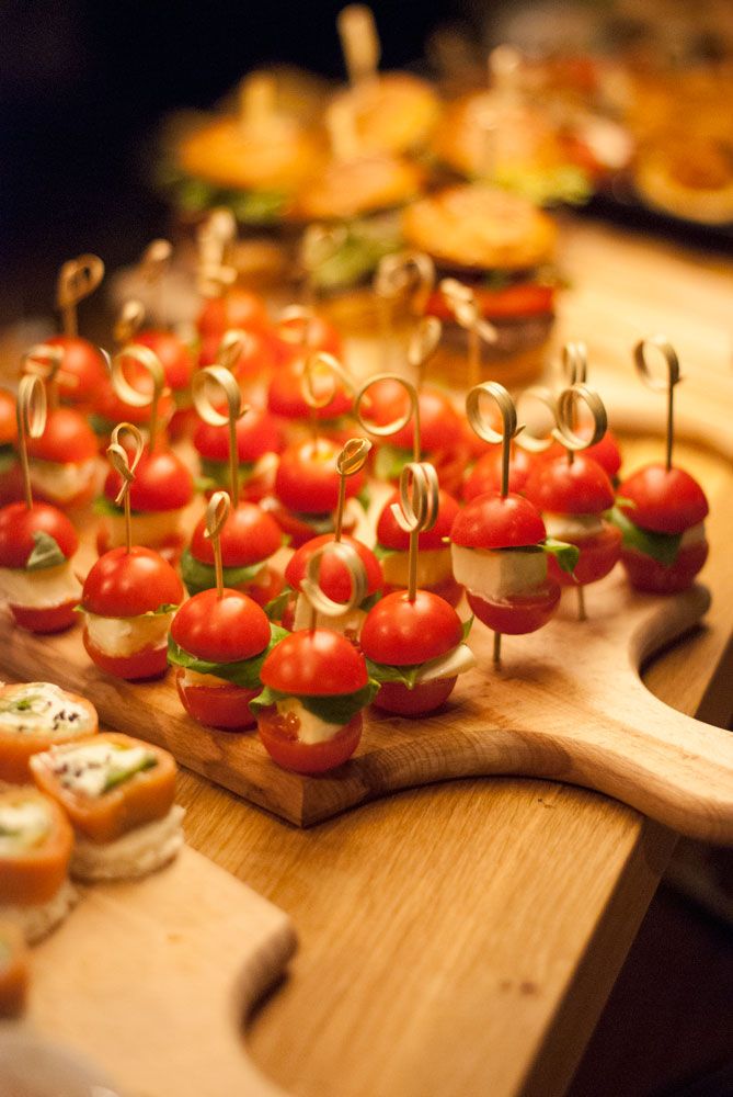 many small appetizers are arranged on a cutting board with toothpicks in them