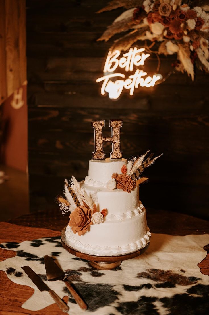 a white cake sitting on top of a table next to a wooden sign that says better together