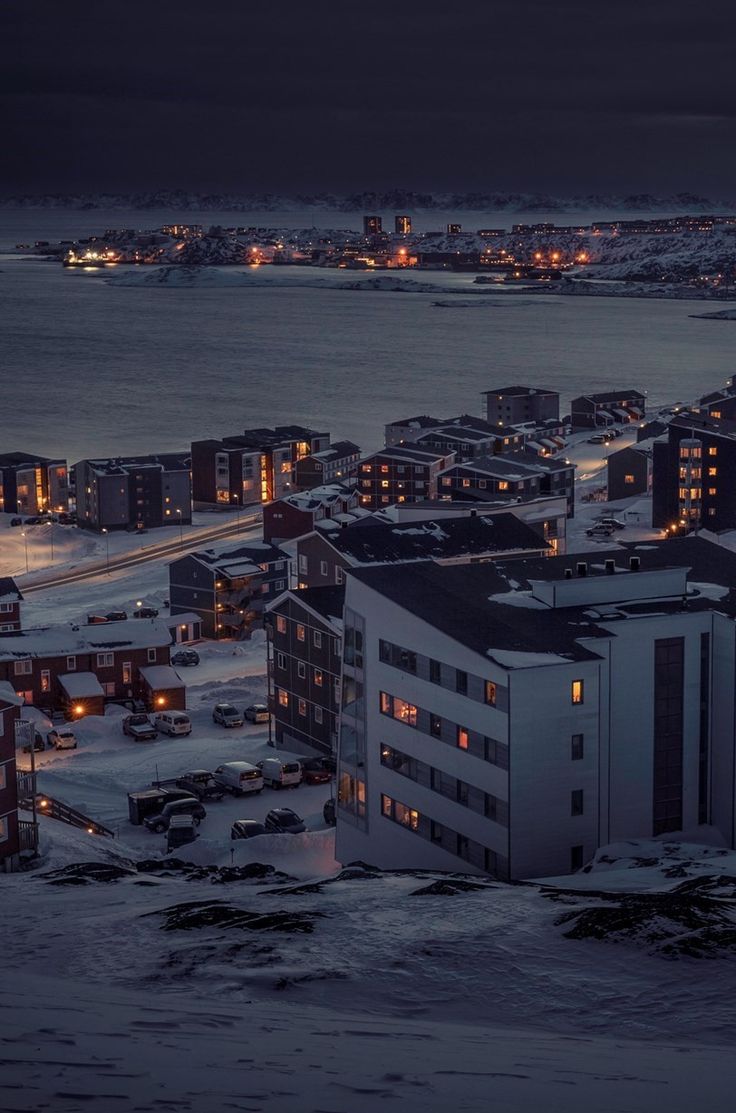 an aerial view of a city at night with snow on the ground and buildings lit up