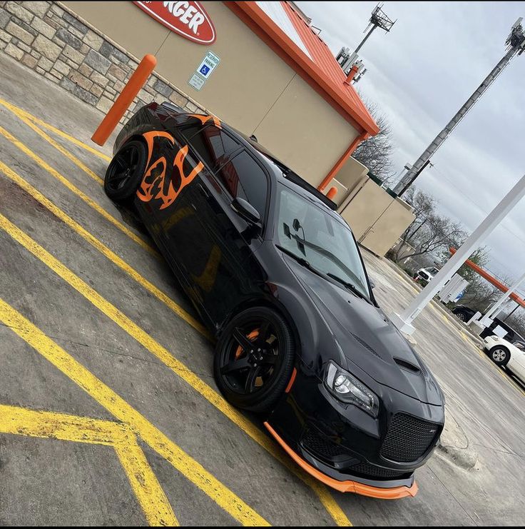 a black sports car parked in front of a fast food restaurant with orange lettering on it