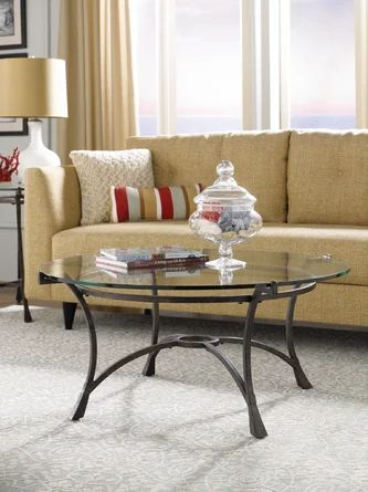 a glass table sitting in front of a couch on top of a carpeted floor