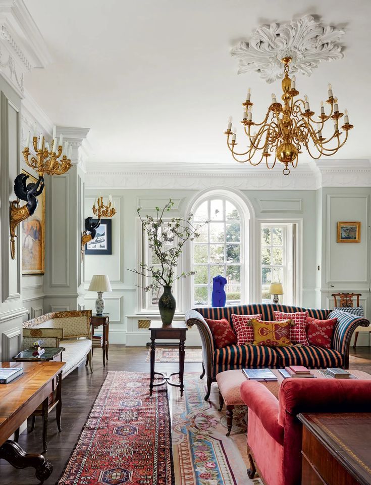 a living room filled with lots of furniture and a chandelier hanging from the ceiling