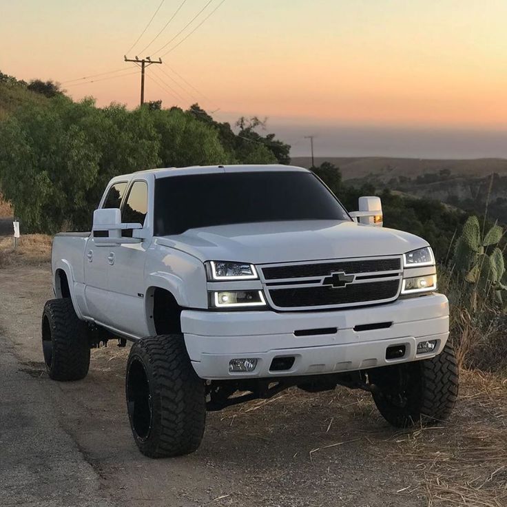 a white truck parked on the side of a dirt road