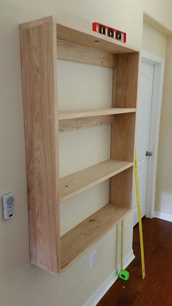 a wooden book shelf sitting on top of a hard wood floor next to a white door