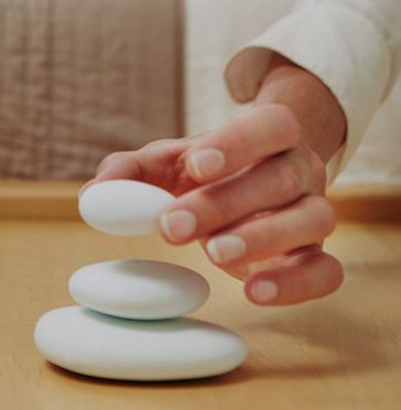 a person stacking three white eggs on top of each other