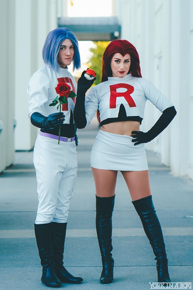 two women dressed in costumes standing next to each other on the sidewalk with one holding a rose