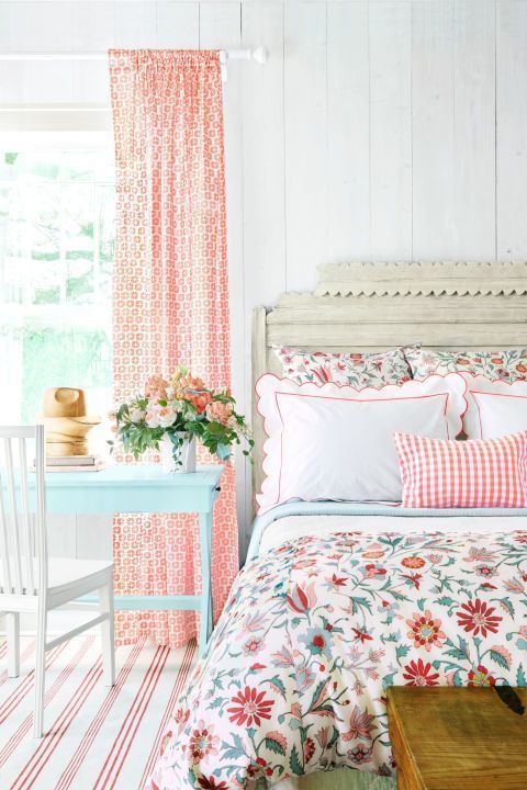 a bedroom with pink and white bedding, floral print comforter, striped rugs and curtains