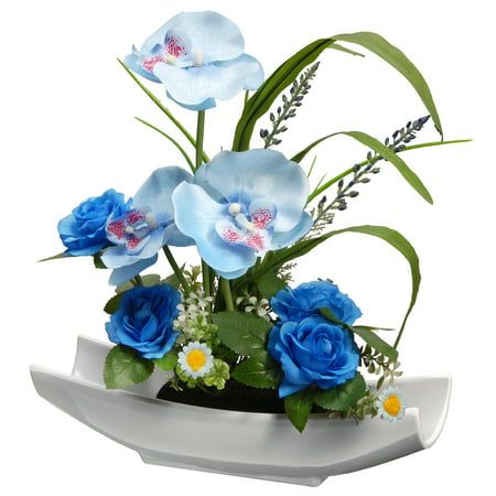 blue flowers and greenery are arranged in a white vase on a table or shelf