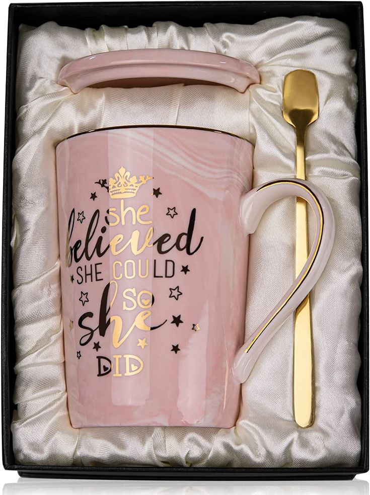 a pink coffee mug in a gift box with a gold spoon and fork on it