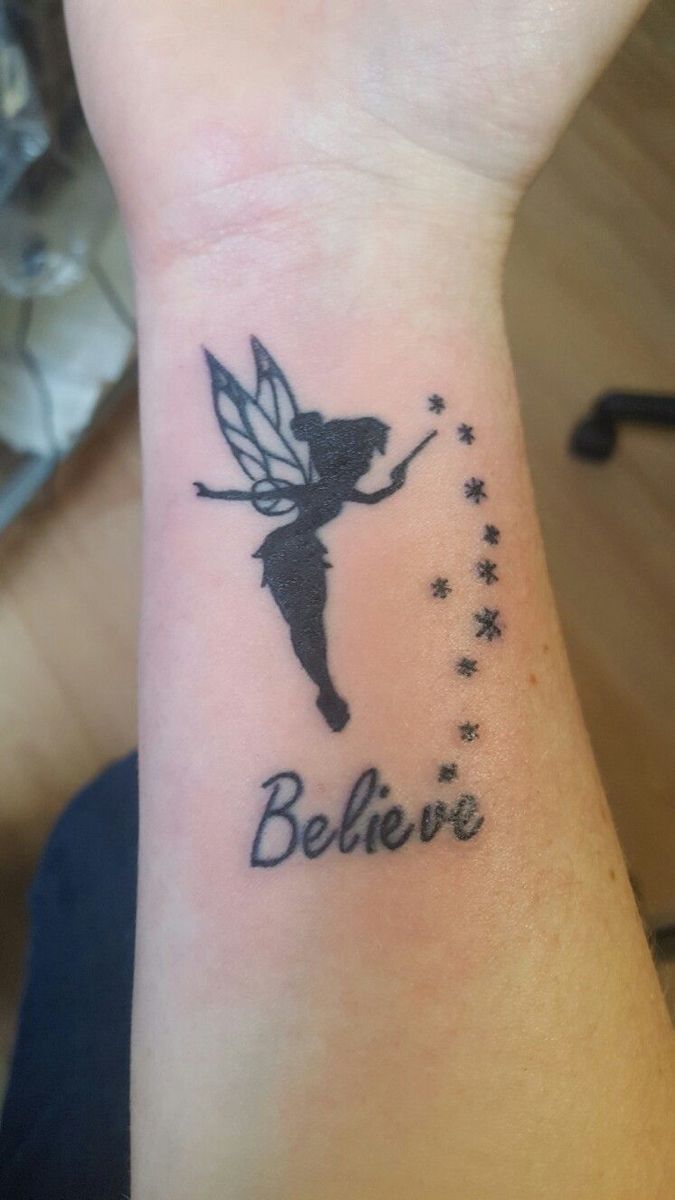 a small wrist tattoo with the words believe and a tinkerbell fairy on it