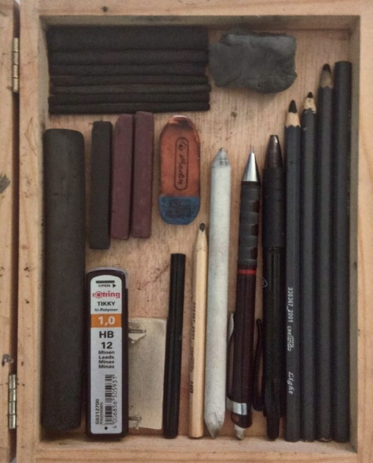 a wooden box filled with different types of pens and pencils