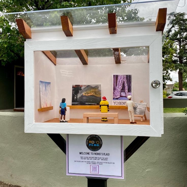 a display case with miniature people and paintings on the wall in it's center