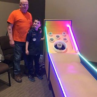 an older man standing next to a young boy in front of a game console