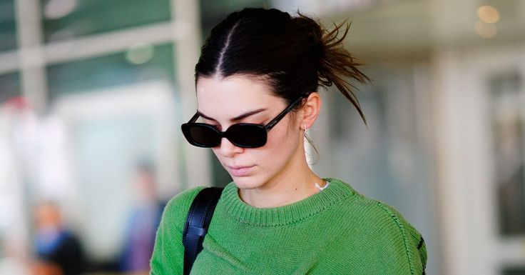 a woman with sunglasses on her head is looking at her cell phone while walking down the street