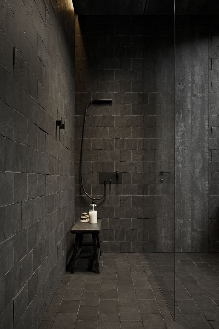 a black tiled bathroom with a shower head