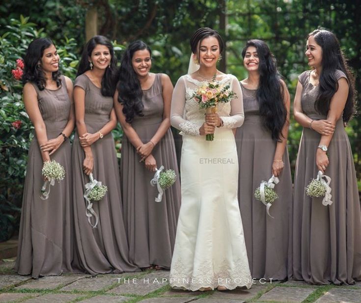 a group of women standing next to each other holding bouquets and smiling at the camera