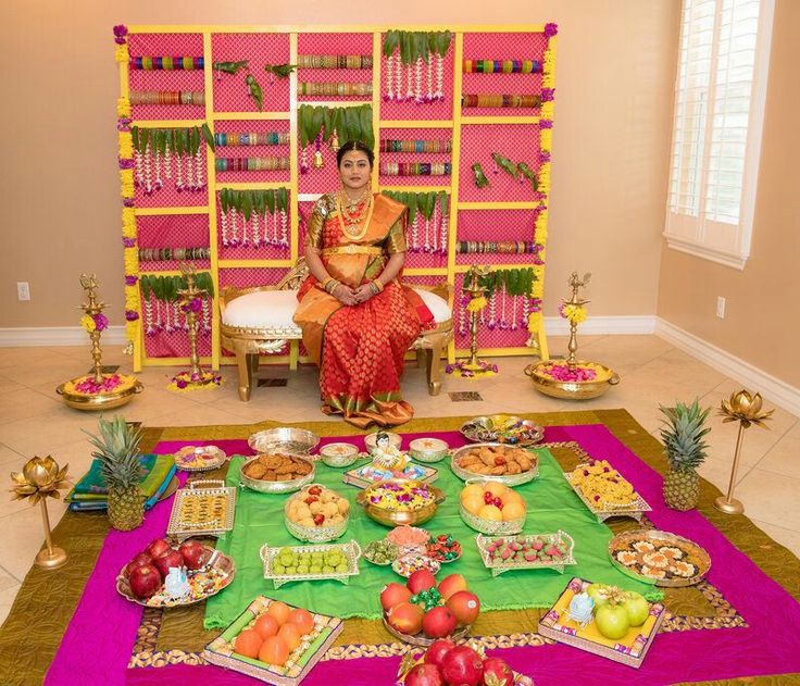 a woman sitting on a chair in front of a table filled with fruit and desserts