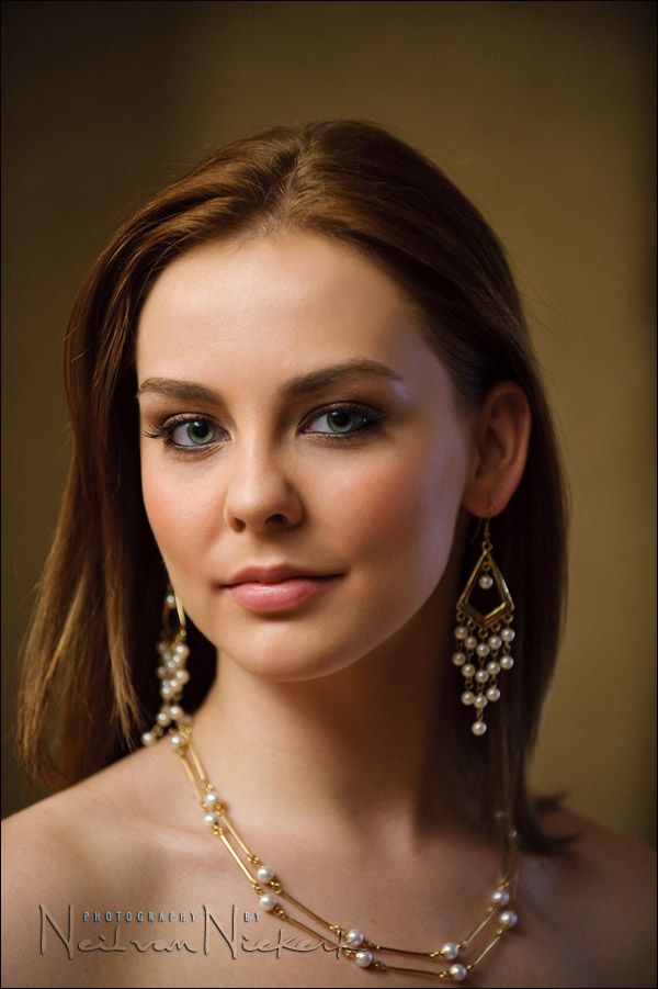 a young woman wearing pearls and gold jewelry