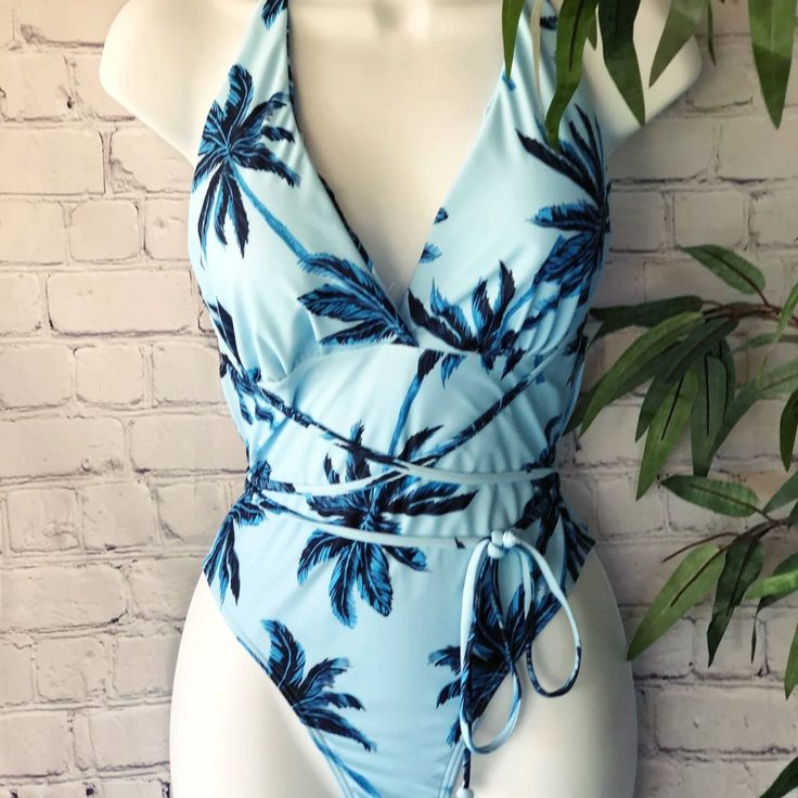 Find Yourself Under The Palms! In Ygb's Coco Palm One Piece Swimsuit. Available In Light Blue And Lilac. It Has A Sleek Stretch Knit You Will Love! It Shapes Into A Haltered V Neck Plunge, Features Cute Strappy Halter Details That Wrap Around The Waist With An Open-Back Cut, High-Cut Legs With Modest Bottom Coverage. New Style Fit: See Chart Blue Palm Tree Print Swimwear For Summer, Blue Palm Tree Print Swimwear For Vacation, Blue Palm Tree Print Swimwear For Pool, Blue Swimwear With Palm Tree Print For Pool, Blue Palm Tree Print Swimwear, Beachy Blue One-piece Bodysuit, Summer Style Blue Bodysuit For Beach Party, Blue Summer Bodysuit For Beach Party, Blue Bodysuit For Beach Party Season