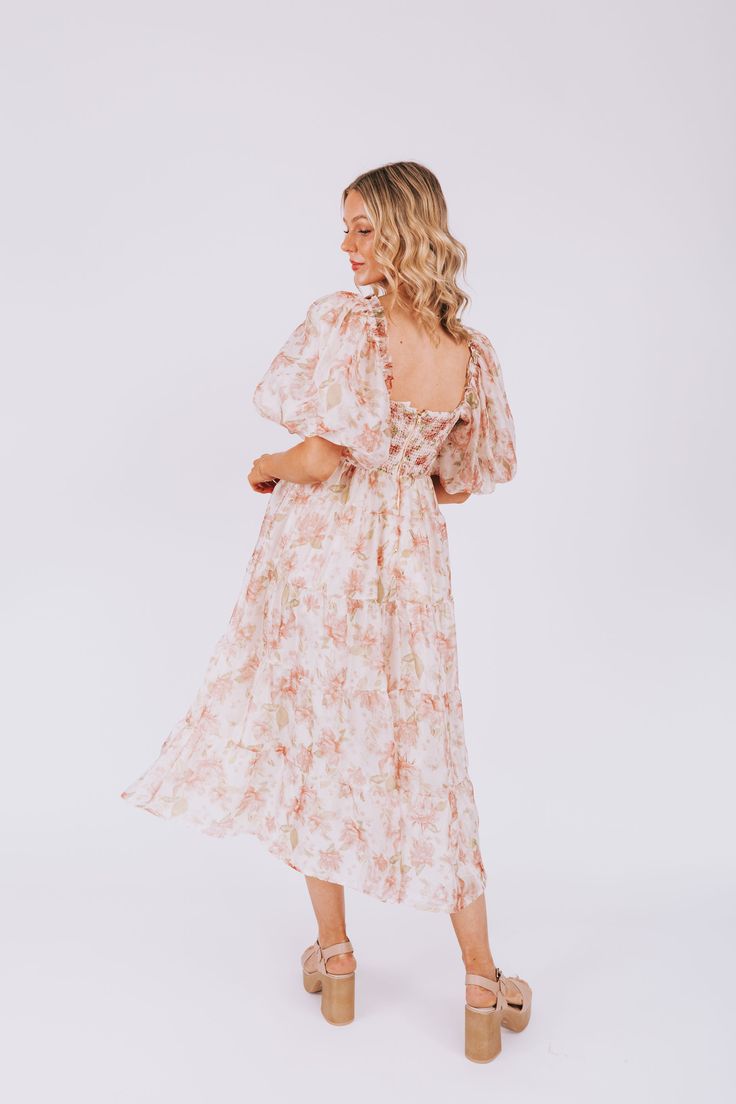 Introducing the EXCLUSIVE "Bring The Romance Dress" from One Loved Babe. This peach floral midi dress features ruffle detailing on the sleeve and a tiered skirt, while the stretchy bust ensures a comfortable and flattering fit. Available in sizes XS-6XL, this dress is perfect for any occasion. Details Textured fabric along bust Exaggerated puff sleeve Corset inspired Lined Invisible zipper back closure Shired back Piping details Ruffle details along sleeve Tiered skirt Sizing *Measurements are t Peach Floral Print Summer Dress, Festive Peach Floral Embroidered Dress, Floral Peach Dress, Peach Long Sleeve Floral Print Dress, Pink Floral Print Dresses With 3/4 Sleeve, Whimsical Pink Floral Print Dress, Romance Dress, Nursing Friendly Tops, Nursing Friendly Dress