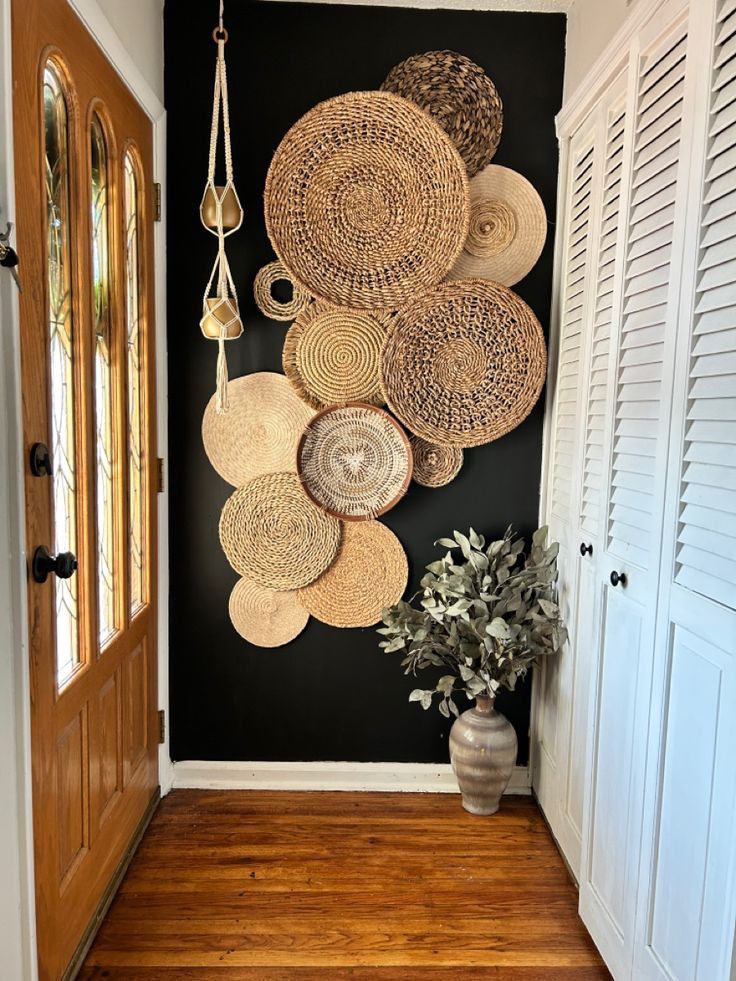 a wall with baskets hanging on it and a potted plant next to it in front of the door