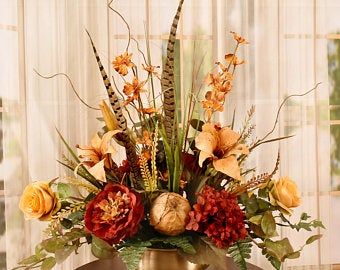 a vase filled with lots of flowers on top of a wooden table next to a window