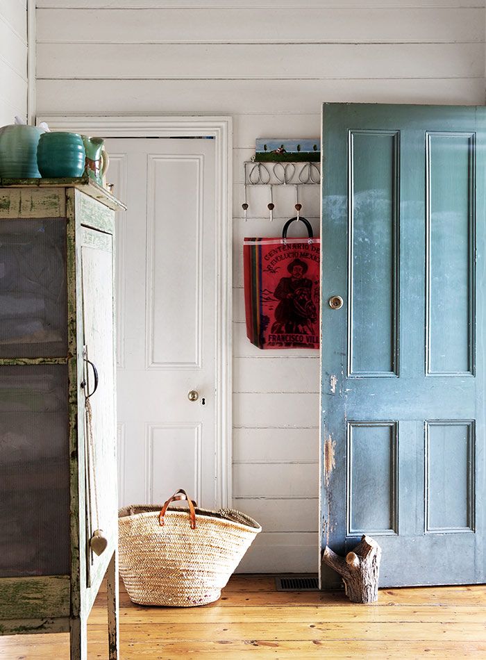 a blue door in a white room next to a basket