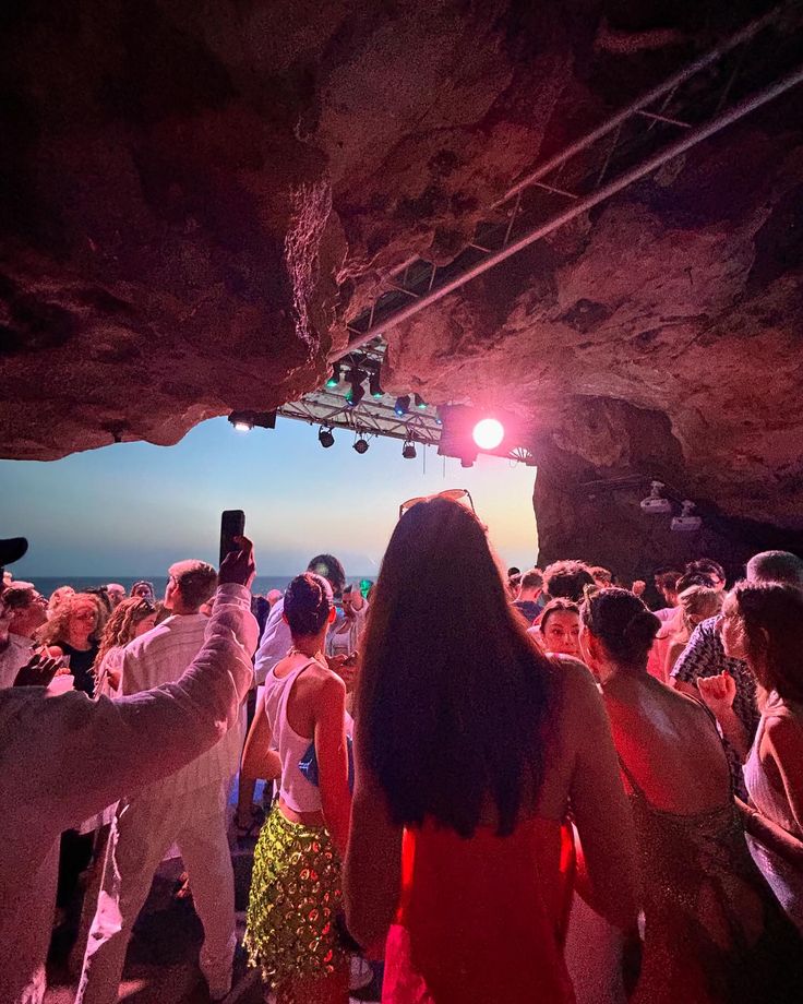 a group of people standing in front of a cave