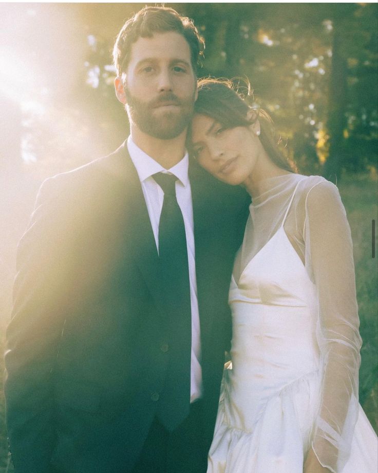 a bride and groom pose for a photo in front of the sun at their wedding