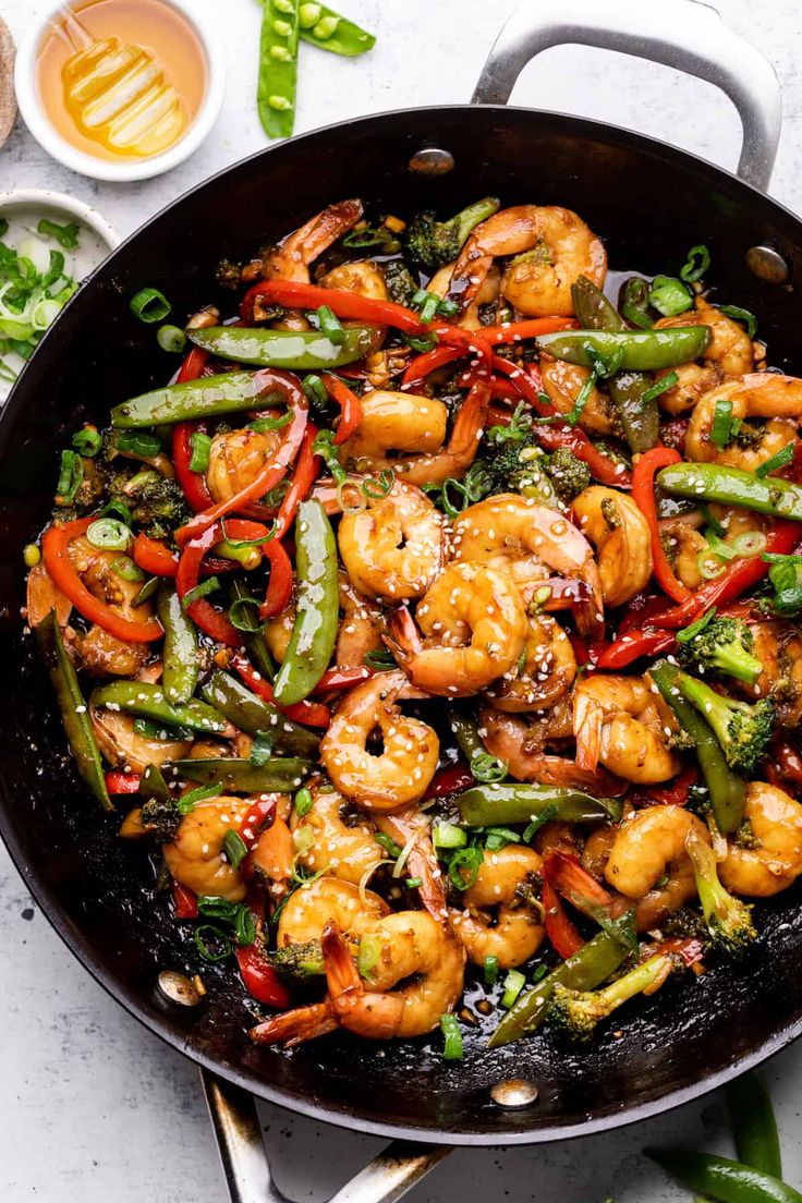 shrimp and vegetable stir fry in a skillet with tongs on the side, ready to be eaten