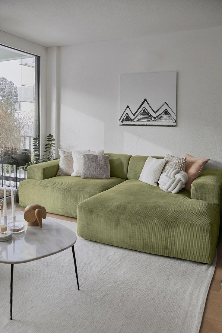 a living room with green couches and white rugs in front of large windows