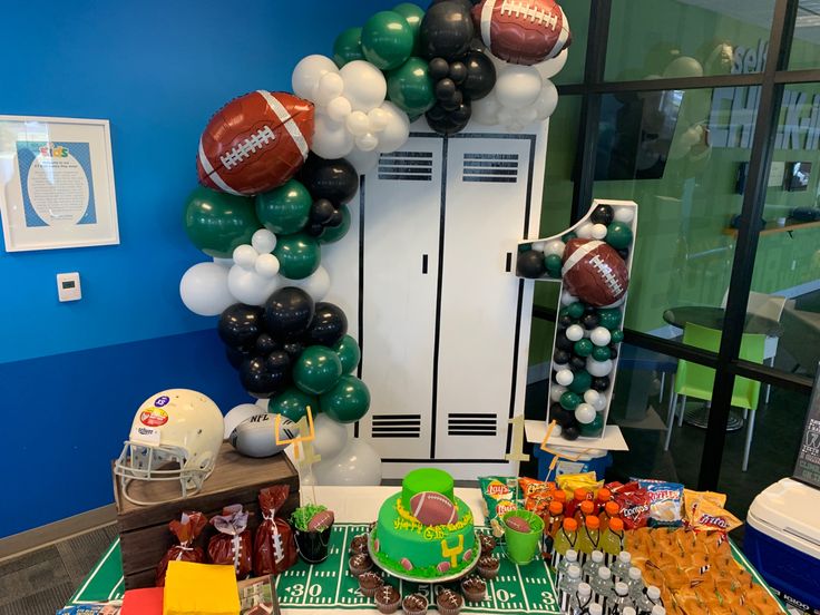 a football themed party with balloons, cake and snacks on a table in front of a locker