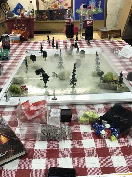 a table topped with a game board and lots of toys on top of checkered cloth