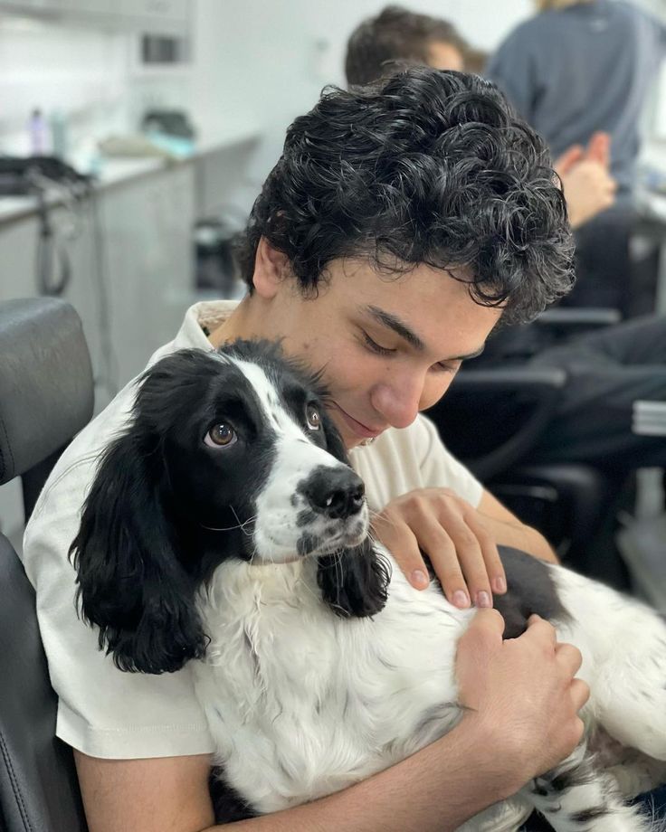 a man holding a black and white dog in an office