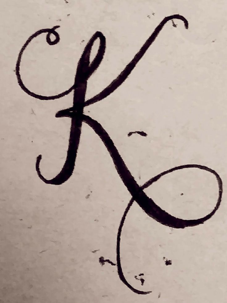 the letter k is drawn on paper with black ink and it appears to be cursive