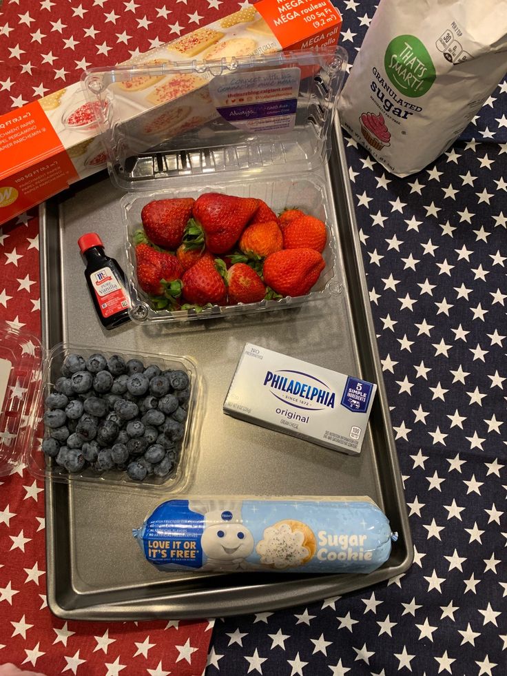 a tray with strawberries, blueberries, yogurt and other food items