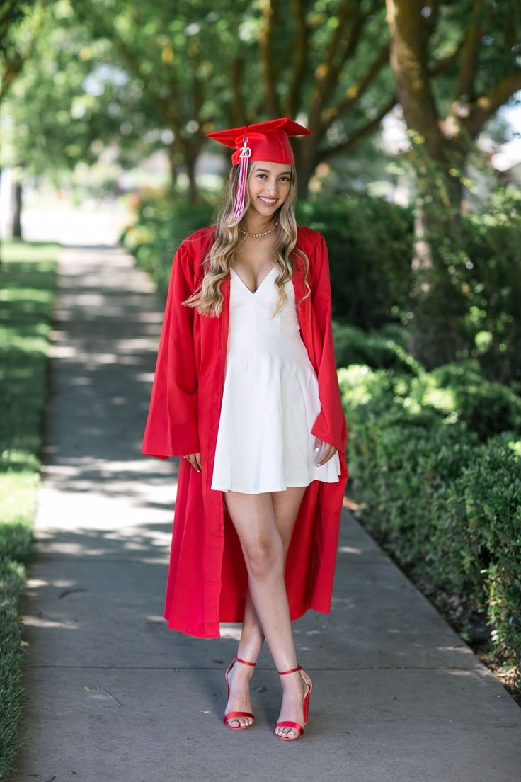 a woman in a graduation gown and cap is standing on the sidewalk with her legs crossed